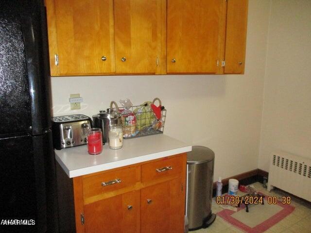 kitchen with radiator heating unit and black fridge