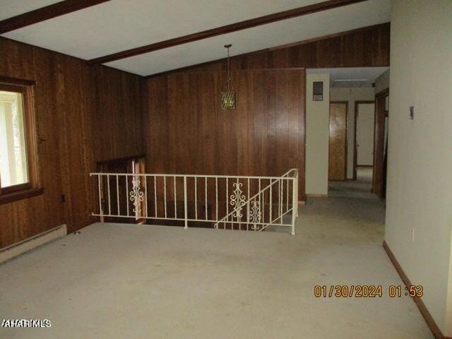 unfurnished room with lofted ceiling with beams, carpet floors, wooden walls, and a baseboard heating unit