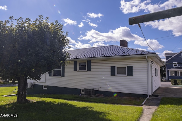 view of side of home with cooling unit and a yard