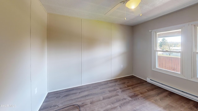 empty room with ceiling fan, hardwood / wood-style floors, and a baseboard heating unit