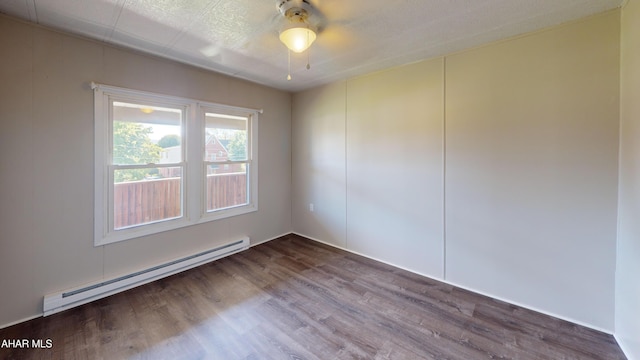 empty room featuring hardwood / wood-style flooring and a baseboard heating unit