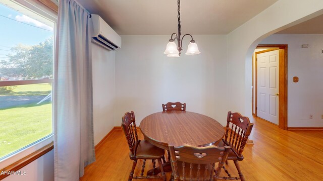 dining room featuring a chandelier, light hardwood / wood-style flooring, and a wall unit AC