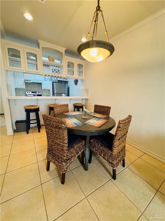 dining space with light tile patterned floors and crown molding