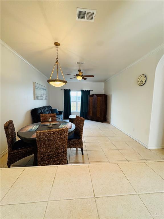 tiled dining space with crown molding and ceiling fan