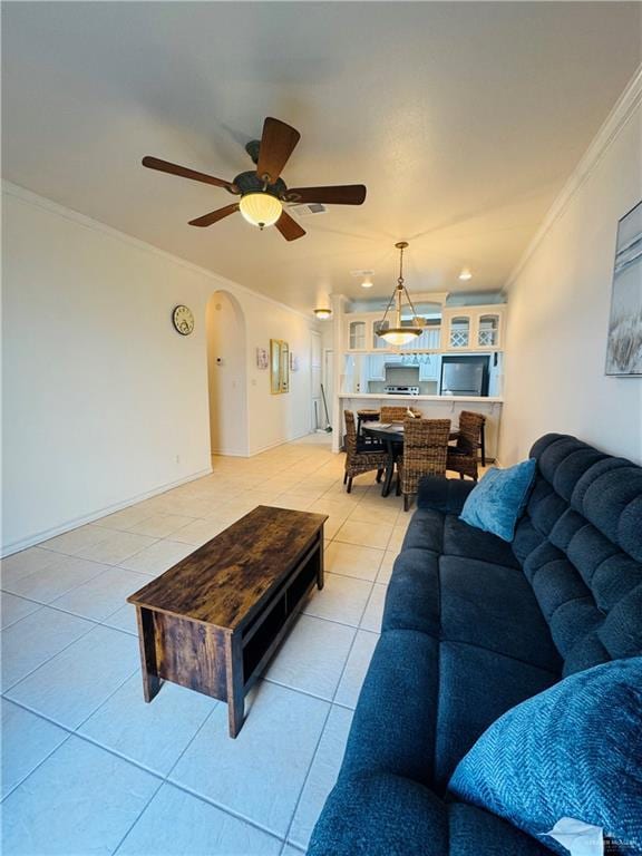 tiled living room with ceiling fan and ornamental molding