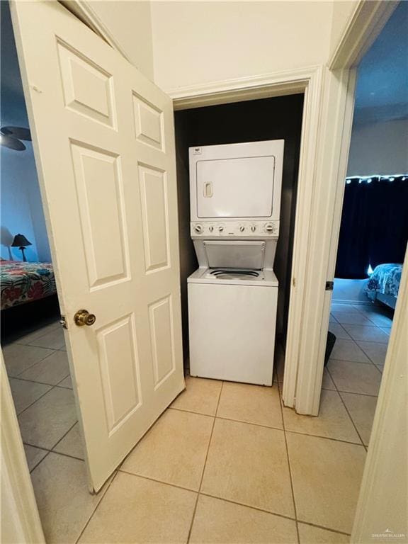 clothes washing area featuring light tile patterned flooring and stacked washing maching and dryer