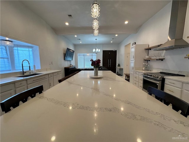 kitchen with sink, range hood, decorative light fixtures, white cabinetry, and a breakfast bar area