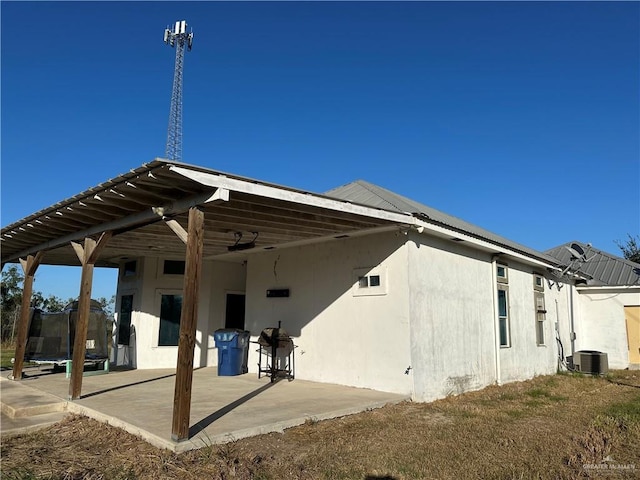 rear view of house with a trampoline, cooling unit, and a patio area