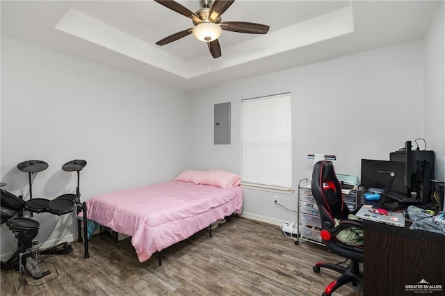 bedroom featuring electric panel, ceiling fan, a raised ceiling, and hardwood / wood-style floors