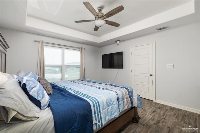 bedroom with ceiling fan, a raised ceiling, and dark hardwood / wood-style flooring