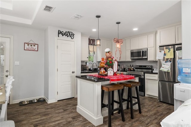 kitchen with dark wood-type flooring, white cabinetry, a center island, and stainless steel appliances