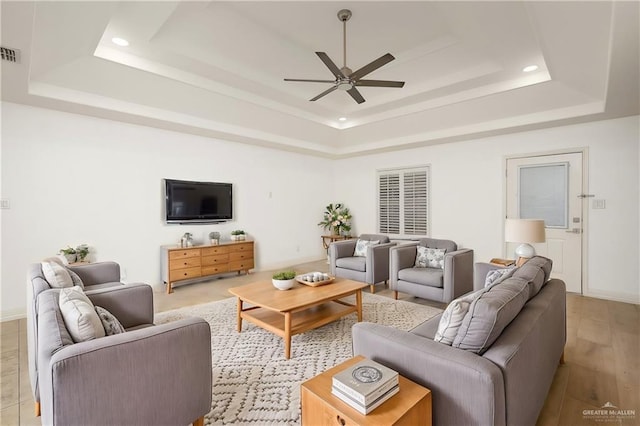 living room with recessed lighting, visible vents, a raised ceiling, and a ceiling fan