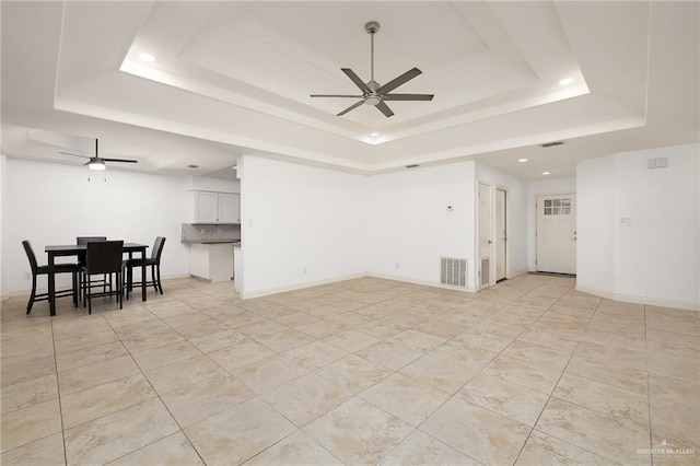 living room featuring visible vents, ceiling fan, baseboards, a tray ceiling, and recessed lighting