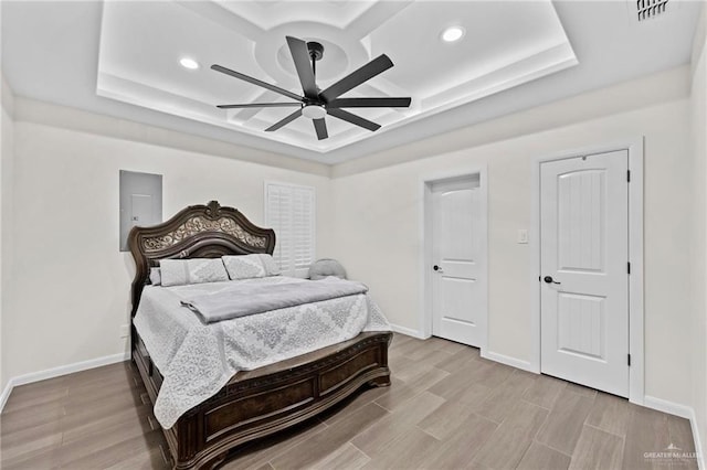 bedroom featuring electric panel, a tray ceiling, ceiling fan, and coffered ceiling