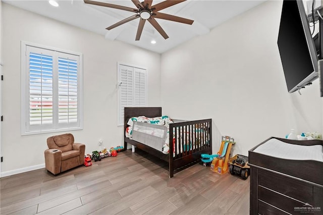 bedroom featuring ceiling fan and a nursery area