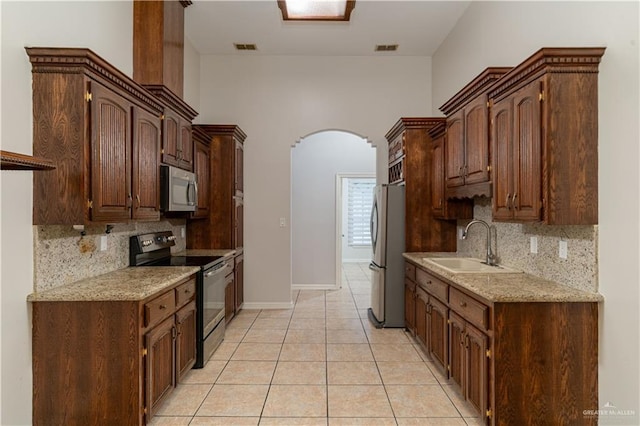 1711 Esperanza Ave, Hidalgo, TX 78557 - kitchen featuring stainless steel appliances, arched walkways, a sink, decorative backsplash, and light tile patterned flooring