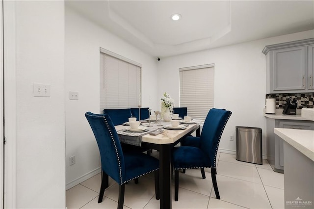 tiled dining area with a raised ceiling