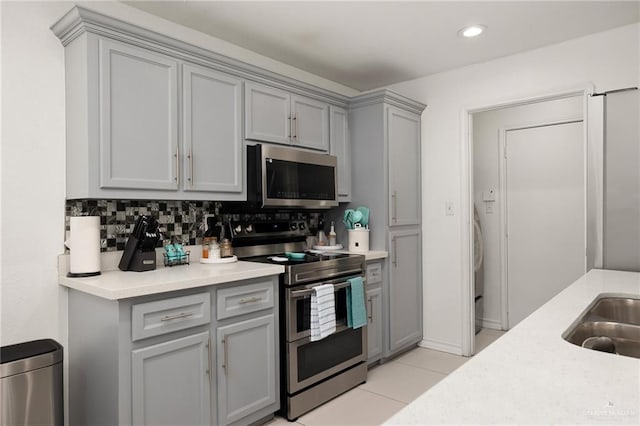 kitchen featuring tasteful backsplash, stainless steel appliances, sink, gray cabinets, and light tile patterned flooring