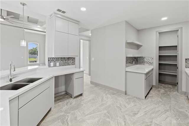 kitchen with kitchen peninsula, decorative light fixtures, tasteful backsplash, and sink