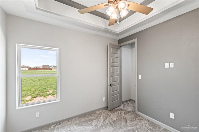 spare room with a raised ceiling, ceiling fan, and a healthy amount of sunlight