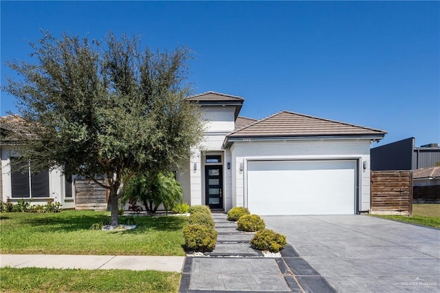 view of front of home with a front yard, a tiled roof, an attached garage, and driveway