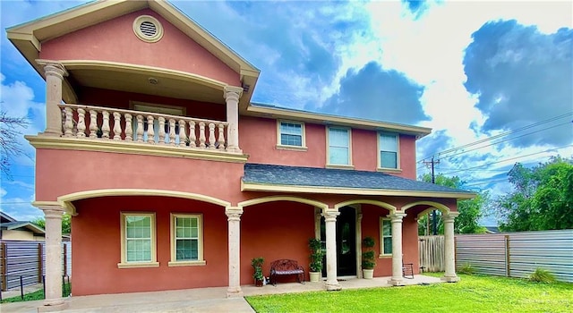 view of front of house with a balcony and a front lawn