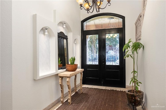 tiled entryway with a chandelier and french doors