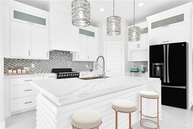 kitchen featuring white cabinetry, decorative light fixtures, light stone countertops, and a kitchen island with sink