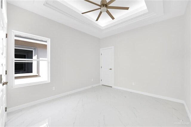 unfurnished room with ceiling fan and a tray ceiling