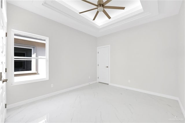 empty room featuring a tray ceiling and ceiling fan