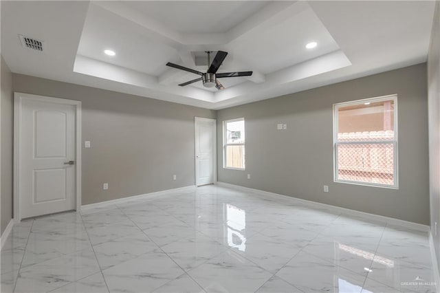 unfurnished room featuring ceiling fan and a tray ceiling