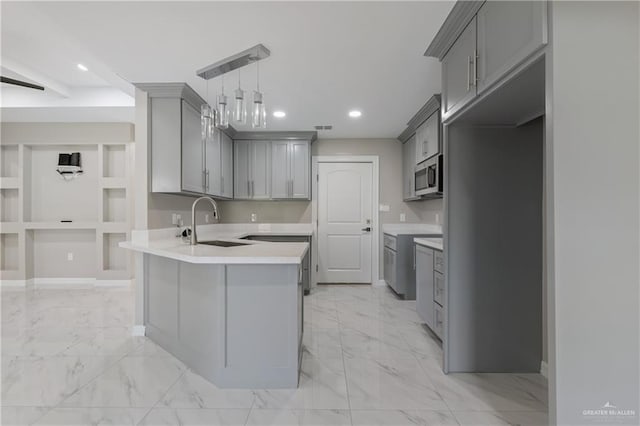 kitchen featuring kitchen peninsula, sink, hanging light fixtures, and gray cabinetry