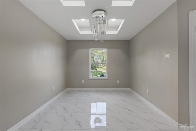 spare room featuring a skylight and a chandelier