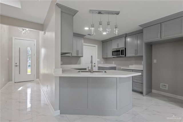 kitchen with hanging light fixtures, gray cabinets, sink, and kitchen peninsula