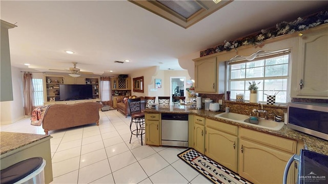 kitchen featuring stainless steel appliances, light tile patterned flooring, a sink, ceiling fan, and a peninsula