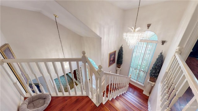 stairway featuring high vaulted ceiling, plenty of natural light, a chandelier, and wood finished floors