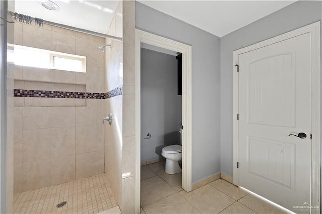 bathroom with tile patterned flooring, toilet, and tiled shower