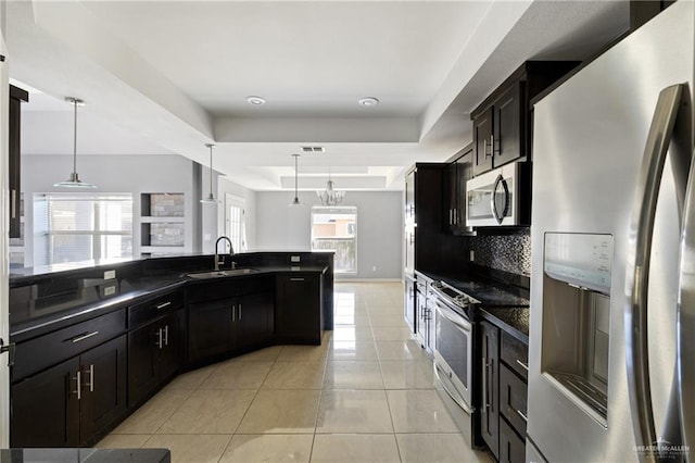 kitchen featuring stainless steel appliances, a raised ceiling, sink, and decorative light fixtures