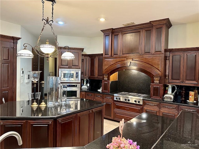 kitchen featuring tasteful backsplash, appliances with stainless steel finishes, a kitchen island, pendant lighting, and dark stone counters