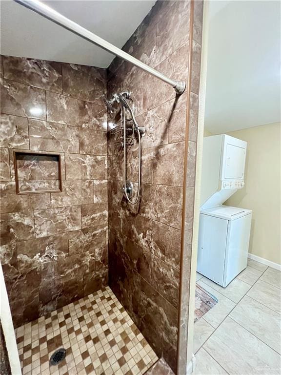 bathroom featuring a tile shower, stacked washer and dryer, and tile patterned flooring