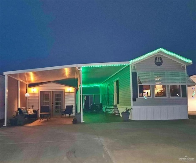 back house at twilight with french doors and a patio