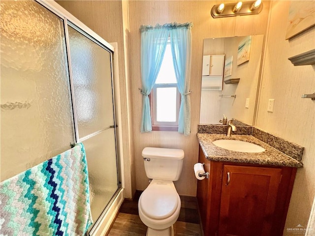 bathroom with hardwood / wood-style flooring, vanity, toilet, and a shower with door