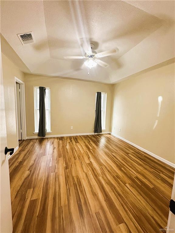 empty room with ceiling fan, hardwood / wood-style floors, and a textured ceiling