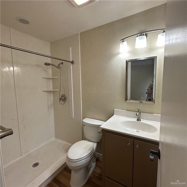 bathroom featuring wood-type flooring, toilet, vanity, and a shower