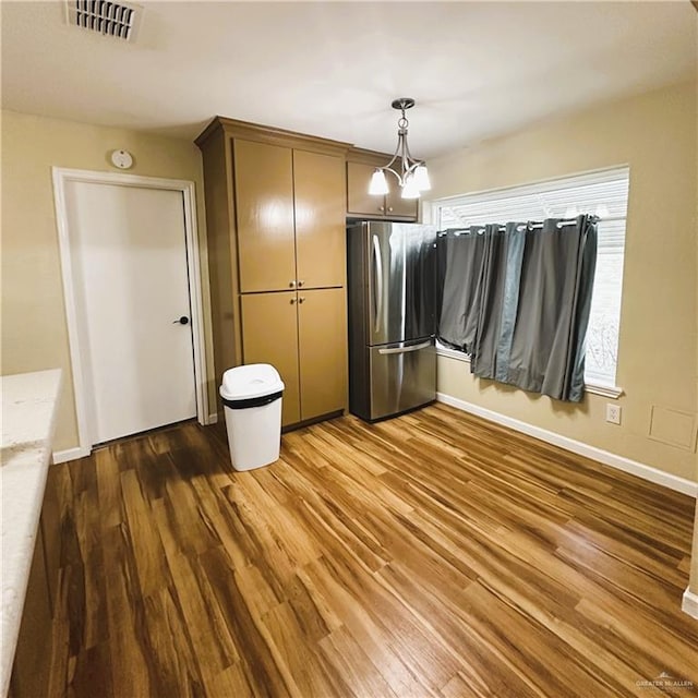 interior space featuring hanging light fixtures, a notable chandelier, dark hardwood / wood-style floors, and stainless steel fridge