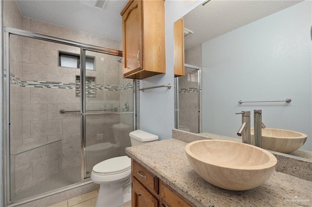 bathroom featuring a textured ceiling, vanity, a shower with door, tile patterned flooring, and toilet