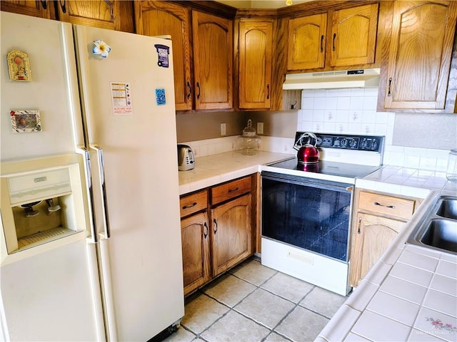 6213 N 17th St, Mcallen, TX 78504 - kitchen with white appliances, under cabinet range hood, tile counters, tasteful backsplash, and light tile patterned floors