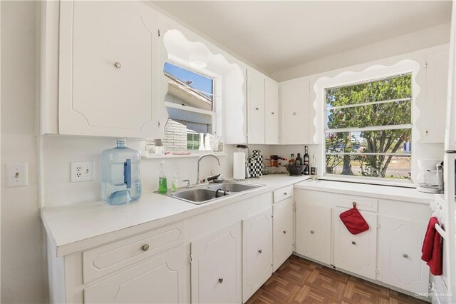 kitchen with sink, white cabinets, and dark parquet floors