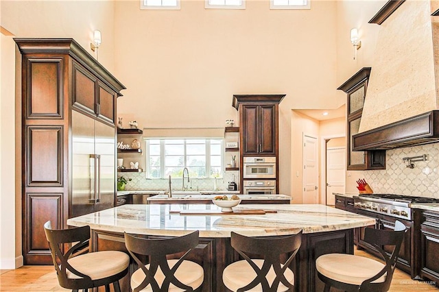 4835 Bryan Rd, Palmhurst, TX 78573 - kitchen featuring a high ceiling, a kitchen breakfast bar, open shelves, dark brown cabinetry, and premium range hood