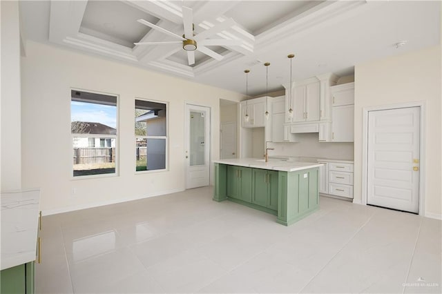 kitchen with coffered ceiling, pendant lighting, a center island with sink, white cabinets, and green cabinets